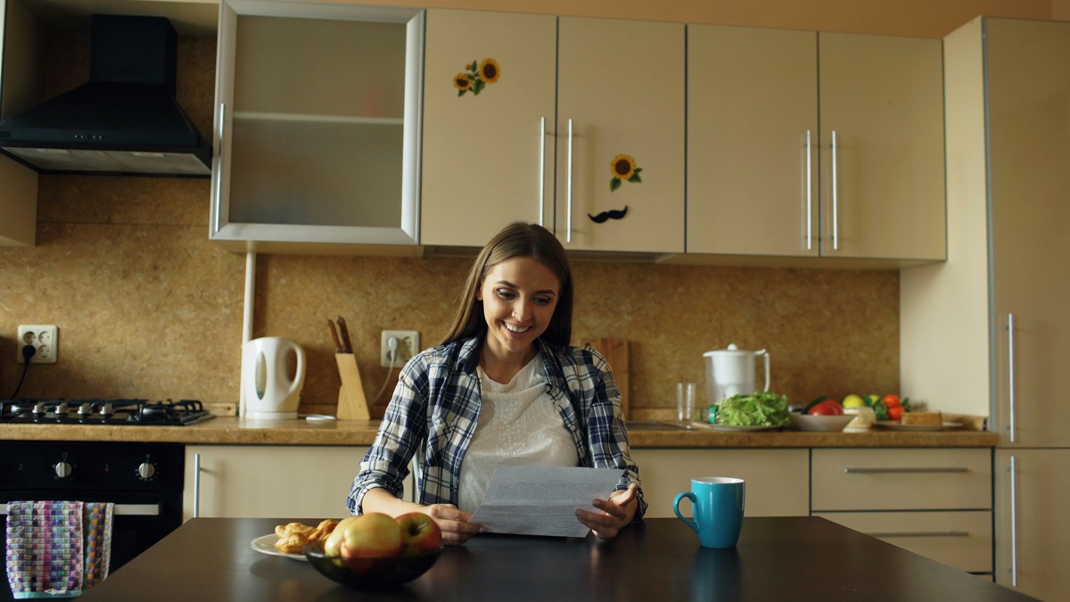 Young woman reviewing a document at her kitchen table
