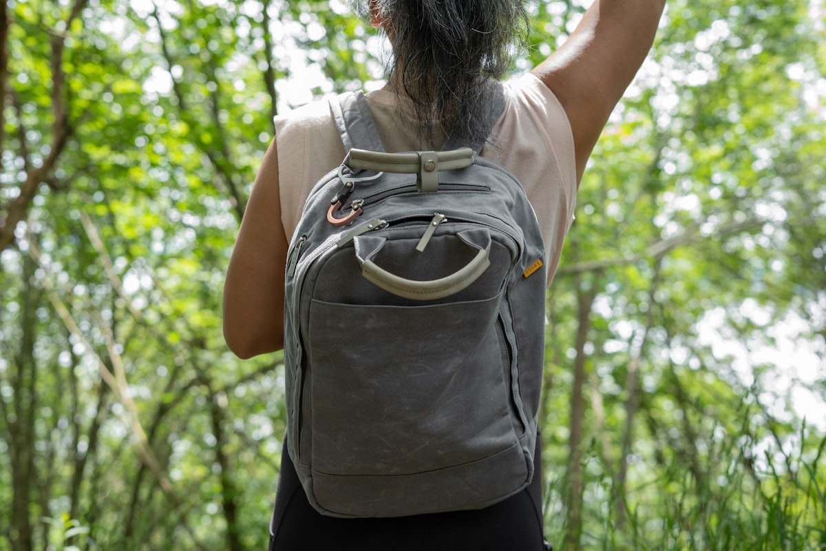 Young woman hiking with backpack on outdoor trail, preparing for physical activity
